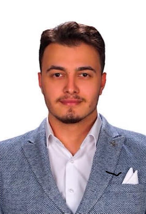 Portrait d’Ayhan Uzundal portant une veste gris-bleu et une chemise blanche